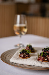 Plated appetizers with a glass of white wine on a table.