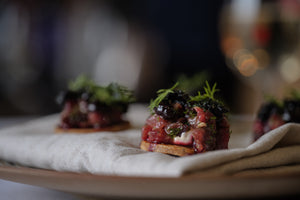Plated dish of small appetizers on a white cloth with a blurred background