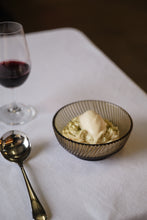 Load image into Gallery viewer, Bowl of dessert with ice cream and a glass of red wine on a white tablecloth.